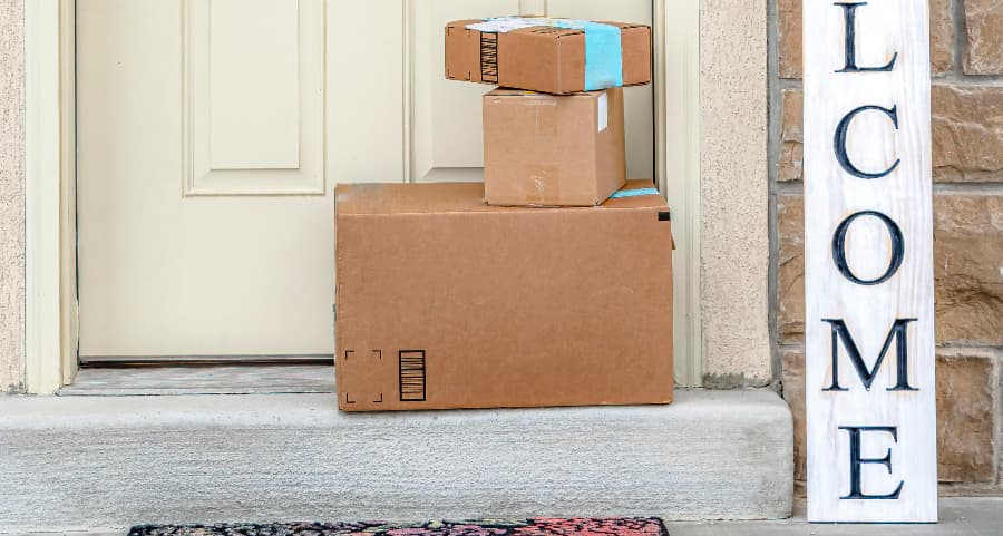 Packages on the doorstep of a home with a welcome sign in College Station